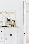 Apothecary jars and rows of hooks on shabby-chic dresser