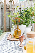 Flowers and vases in shades of yellow and brown on table in garden