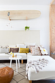 Surfboard on wall above sofa with various scatter cushions