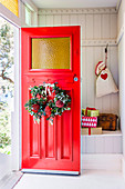 Door wreath with Protea on a red front door for a porch with gifts