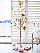 Weihnachtlich dekorierter Ast mit Glitzerfarbe, darunter verpackte Geschenke