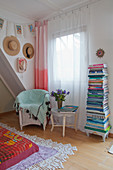 Vorhang mit Farbverlauf und bunter Bücherstapel am Fenster