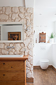 Old chest of drawers used as washstand against partition wall clad with stones