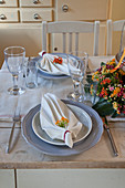 Set table decorated with folded serviettes and flower arrangement
