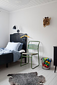 Old green chair next to black bed in child's bedroom