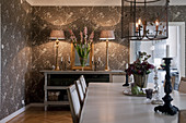 View down dining table to table lamps on console table against floral wallpaper