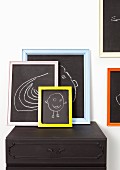 Children's drawings on blackboards with colourful frames on top of black cabinet