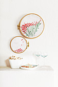 Embroidered floral motif over two embroidery frames on wall