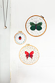Fabric embroidered with butterflies and ladybird in embroidery frames
