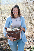 Woman bringing wicker basket as easter nest with easter eggs and easter bunny