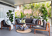 Wooden seating area with gray upholstery on the veranda