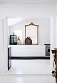 View of white kitchen unit with antique gold frame mirror and cage