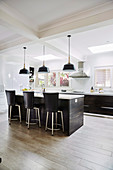 Middle block with bar stools in front of a kitchenette in an open kitchen with porcelain floor tiles in a wood look