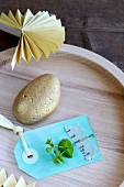Gold-painted pebble and paper tag in wooden dish