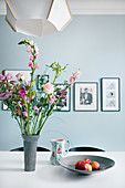 Blumenstrauß in Rosatönen auf dem Esstisch vor hellblauer Wand
