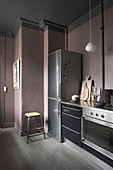 Pale lilac-grey wall in dark kitchen with black cabinets
