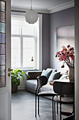 Wohnraum in Grautönen mit Sofa und Blumen auf dem Esstisch