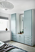 Old fitted cupboards with pale blue doors in bedroom