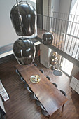 Black pendant lamps above dining table below gallery levels