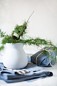 Larch twigs in white jug and gifts wrapped in blue fabric