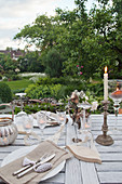 Mit Kerzen und Windlichtern gedeckter Tisch im Garten