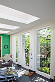 Living room with skylights and floor-to-ceiling windows overlooking garden