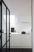 Blick durch geöffnete Glastür in weiße Einbauküche