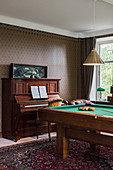 Piano and pool table in masculine living room