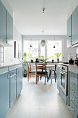 Pale blue cupboards and dining table next to window in retro kitchen