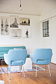 Two blue armchair in front of pictures of sailing boats on wall