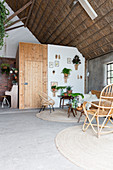 Wicker furniture and plants in living room in old, converted barn