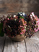 Elderberries and hydrangea flowers in vase on wooden table