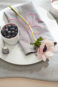 Anemone and bowl of blueberries on place setting