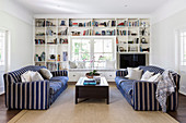 Two opposing blue and white striped sofas in front of a shelf