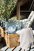 Crockery, cushions and roll of wallpaper in wooden crate