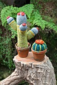 Two crocheted cacti on tree stump in garen