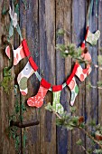 Garland of paper Christmas stockings on weathered wooden door
