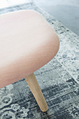 Pink upholstered stool on grey rug