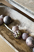 Purple Christmas-tree baubles and artichoke in wooden trough