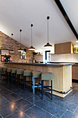 Counter with barstools on black-tiled floor in converted barn