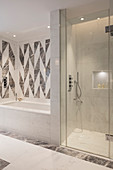 Geometric wall tiles above bathtub in white modern bathroom