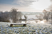 Bench with view of river in wintry landscape