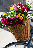 Fahrradkorb mit bunten Blumen und Zierkohl