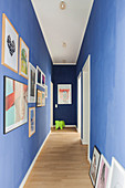 Gallery of pictures on blue walls in corridor