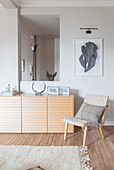 Easy chair and sideboard in front of aperture in grey interior wall