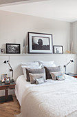 Pictures on ledge above bed in monochrome bedroom
