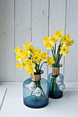 Easter eggs hung from daffodils in blue bottles