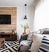 Sofa with patterned pillows and wood paneled wall