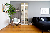 Reading corner, display case and dark sofa against grey wall