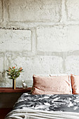 Bed with bedside table in front of concrete wall